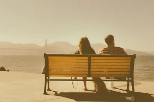 Two people sitting together on a bench at sunset